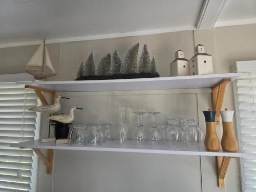 a shelf with glasses and vases on it at Sunrise on the Tamar in Deviot