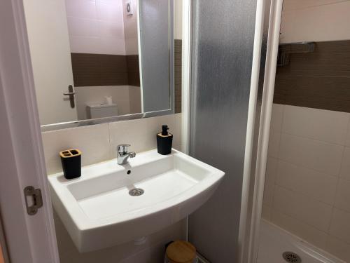 een badkamer met een witte wastafel en een spiegel bij A Casa de Feli in Muros