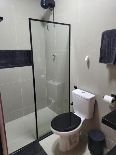 a bathroom with a toilet with a glass shower at Pontal Flat 103 in Coruripe