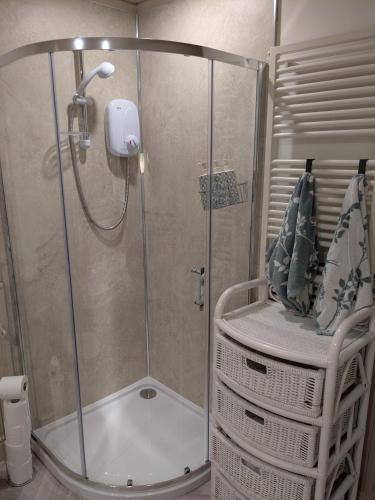 a shower with a glass door with a chair in a bathroom at Holywood Hideaway 2 bedroom retreat in Cultra