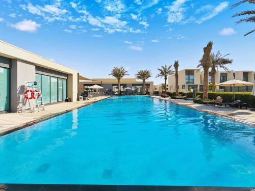 een groot blauw zwembad met palmbomen en gebouwen bij Elegant 4BR Haven I Private & Peaceful in Dubai