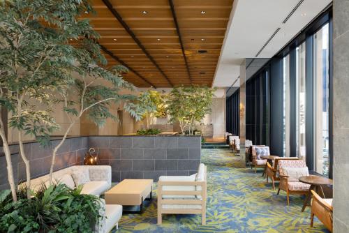 een lobby met tafels, stoelen en planten bij Miyako City Osaka Hommachi in Osaka