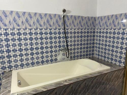 een badkamer met een bad en blauwe en witte tegels bij Lege Bonoua in Bonoua