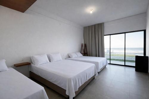 twee bedden in een hotelkamer met uitzicht op de oceaan bij Maraga Bento in Maragogi