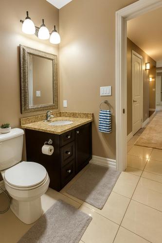a bathroom with a toilet and a sink and a mirror at Executive 2BR Lower Suite Private & Spacious Close to USA Border in Windsor