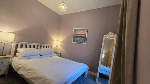 een slaapkamer met een wit bed en een spiegel bij The Maisonette central Buxton in Buxton