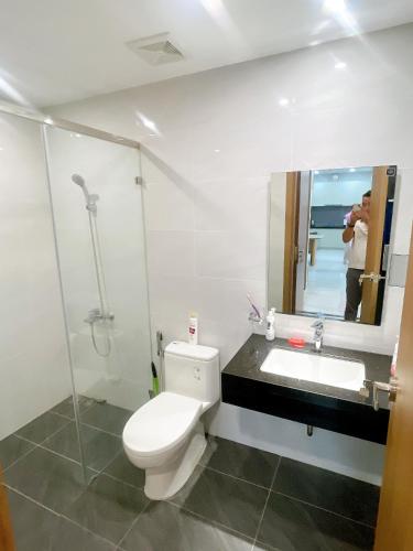 a bathroom with a toilet and a sink and a mirror at Happy One Central in Trạm Chánh An