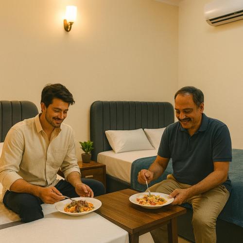 zwei Männer sitzen an einem Tisch mit Teller Essen in der Unterkunft The Atelier G-13 in Islamabad