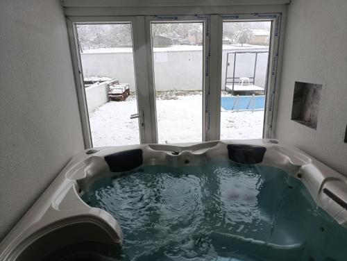 a bath tub in a room with a window at Todorović SPA & bazen in Velereč