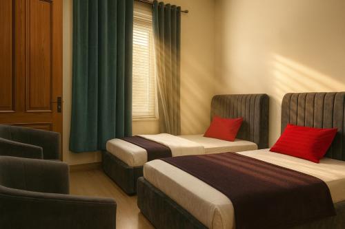 zwei Betten in einem Hotelzimmer mit roten Kissen in der Unterkunft The Atelier G-13 in Islamabad