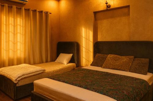 ein Hotelzimmer mit zwei Betten und einem Stuhl in der Unterkunft The Atelier G-13 in Islamabad