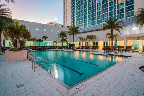 a large swimming pool with palm trees and a building at Skyline Serenity City Views, Pool, Hot Tub & Gym in Fort Myers