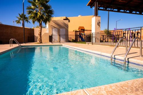 a swimming pool with blue water and a palm tree at Casa Bárbara Totalmente Nueva in Hermosillo