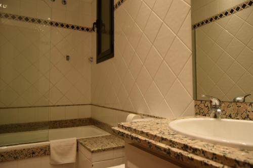 ein Badezimmer mit einem Waschbecken, einer Badewanne und einem Spiegel in der Unterkunft Apartments Historic in Girona