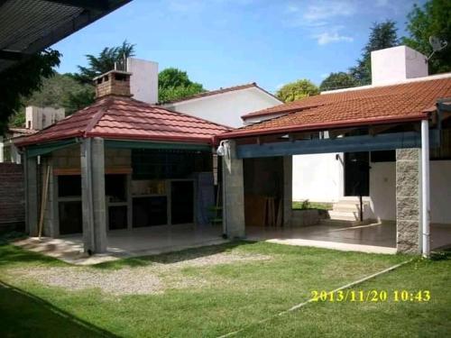 een oud huis met een rood dak en een tuin bij Casa Doña Victoria in Villa Carlos Paz