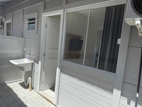 een badkamer met een wastafel en een glazen schuifdeur bij Loft novo e bem localizado in Biguaçu