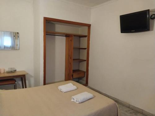 een slaapkamer met een bed en een tv aan de muur bij Florencia Apartamentos y habitaciones in Necochea