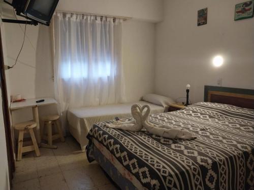 een hotelkamer met twee bedden en een televisie bij Florencia Apartamentos y habitaciones in Necochea