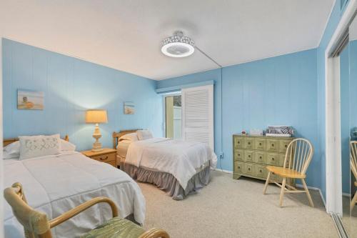 a blue bedroom with two beds and a chair at 2BR Renovated Siesta Key Condo, beach and pool access in Sarasota