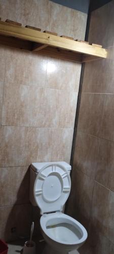 a bathroom with a toilet with a wooden shelf above it at Lumar in Santa Teresita