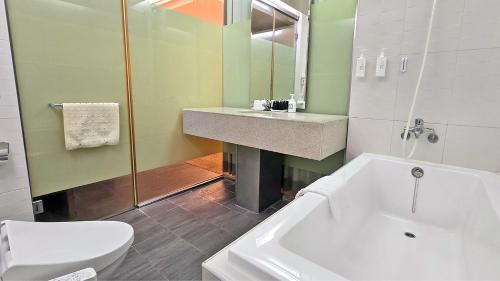 een badkamer met een bad, een wastafel en een toilet bij Kavalan Hotel in Luodong
