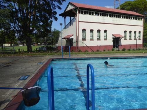 a person swimming in a swimming pool in front of a building at The Red Barn right in the heart of historic Berry in Berry