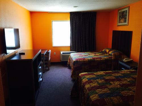 a hotel room with two beds and a desk at Scottish Inn & Suites Hobby Airport in Houston