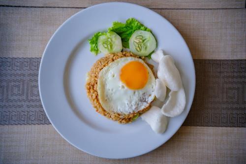 ein Teller mit einem Ei und Gemüse auf einem Tisch in der Unterkunft Kamini Legian Hotel in Legian