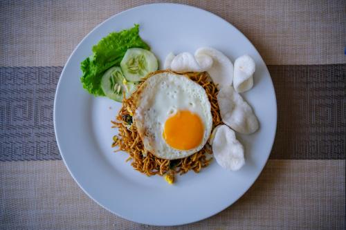 ein Teller mit Essen mit einem Ei und Nudeln in der Unterkunft Kamini Legian Hotel in Legian