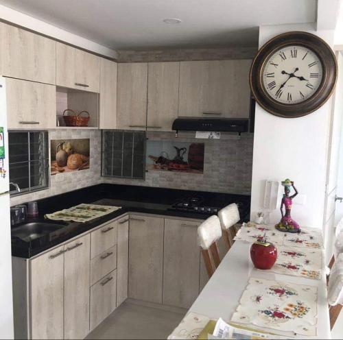 een keuken met een klok aan de muur en een tafel bij Caranday, Las Palmas in Ricaurte