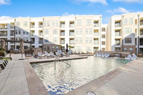 a swimming pool with chairs and buildings in the background at Lux 1B with Pool Near The Star, Legacy West & Toyota in Frisco