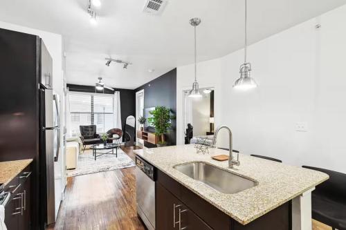 a kitchen with a sink and a living room at Lux 1B with Pool Near The Star, Legacy West & Toyota in Frisco