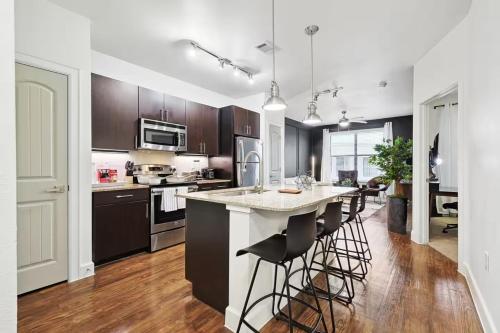 a kitchen with a large island with bar stools at Lux 1B with Pool Near The Star, Legacy West & Toyota in Frisco