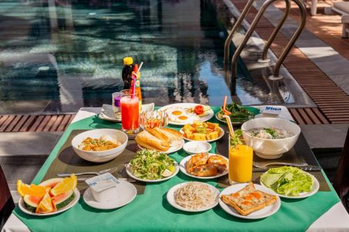 een tafel met borden eten naast een zwembad bij Paradise Boutique Hoi An in Hội An