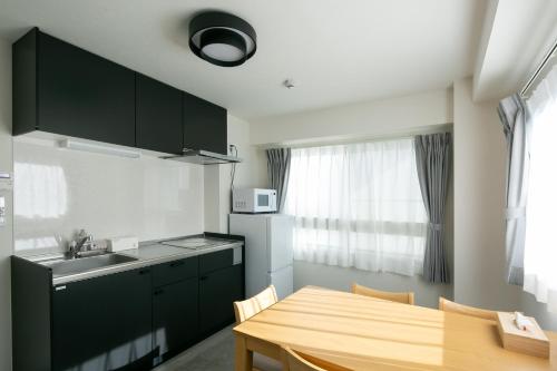 a kitchen with a wooden table and a kitchen with a sink at trive osu monzencho 702 最大5名宿泊可能 大須商店街徒歩スグ in Nagoya