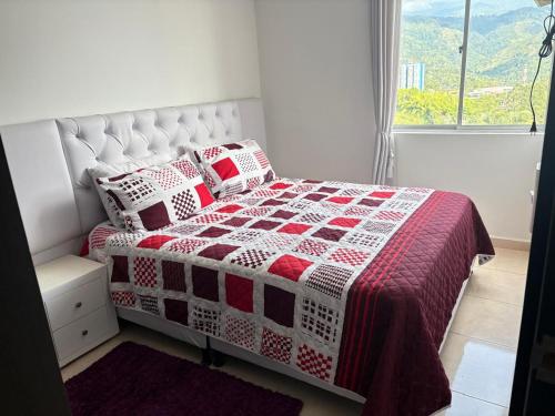 a bedroom with a bed with a red and white quilt at apta estudio oronegro amanecer in Armenia