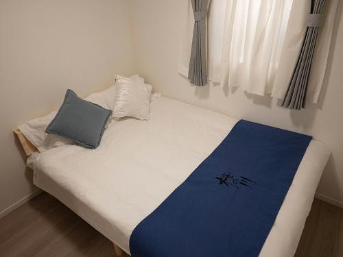 a small bed with a blue and white blanket on it at 桜の川70-41 稲荷町駅 近上野-浅草 2-8人丨 Inaricho Station, Near Ueno, Asakusa 2-8 people in Tokyo