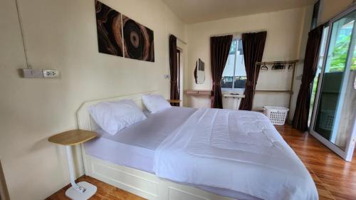 a bedroom with a white bed with a wooden floor at Casa Srithanu in Koh Phangan