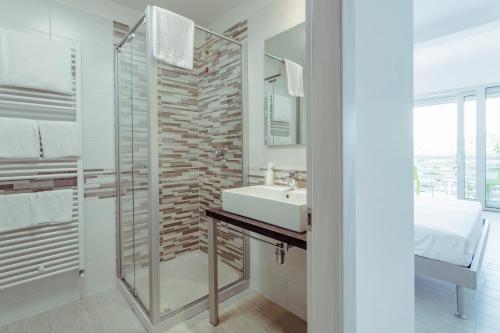 La salle de bains est pourvue d'un lavabo et d'une douche en verre. dans l'établissement Hotel Stella del Benaco, à Manerba del Garda