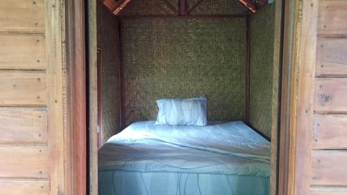 a small bed in a corner of a room at Pengaringan Cottage Cotol in Gitgit