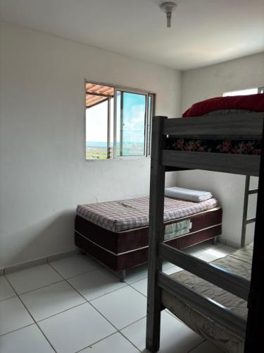 ein Schlafzimmer mit zwei Etagenbetten und einem Fenster in der Unterkunft Apartamento Duplex em Jacumã in Conde