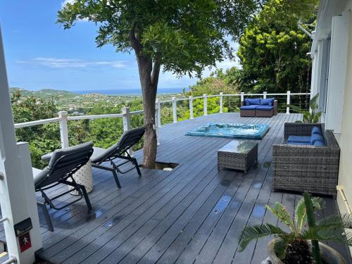 a deck with chairs and a table and a tree at CARIBBEAN SPLENDOR WITH MILLION DOLLAR VIEWS in Christiansted