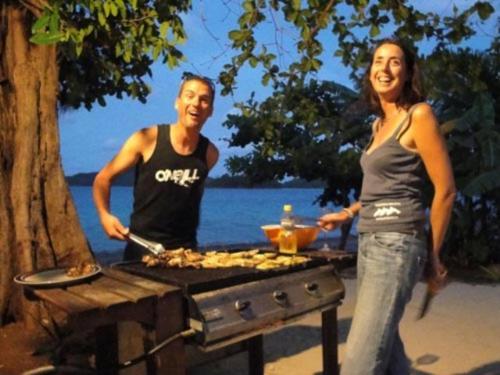 a man and a woman standing next to a grill at Mystic Sands in Utungake