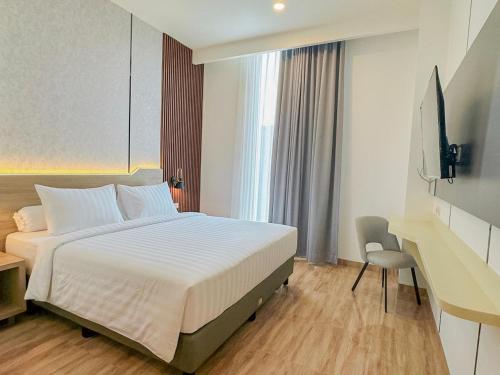 une chambre avec un lit, un bureau et une télévision dans l'établissement Azana Style Hotel Jombang, à Peterongan