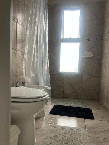 a bathroom with a toilet and a tub and a window at SJ Apart in Corrientes