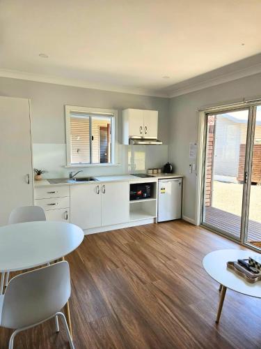 a kitchen with white cabinets and a table and chairs at Parndana Hotel Cabins in Parndana