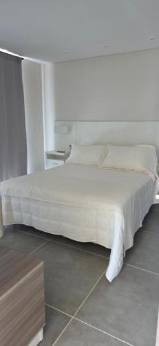 a bedroom with a large white bed and a table at Kilka Departamento 3 Ambientes con Balcón in Mar de las Pampas