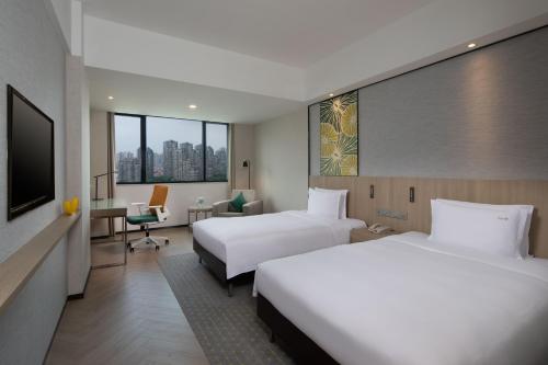 a hotel room with two beds and a television at Holiday Inn Shanghai Vista in Shanghai