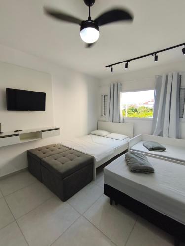 a bedroom with two beds and a flat screen tv at 2 Evangelistas Apartamentos in Cachoeira Paulista