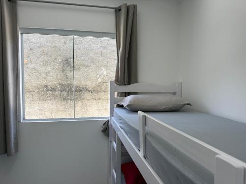 een slaapkamer met een stapelbed en een raam bij Casa nova bem aconchegante e tranquila in Biguaçu